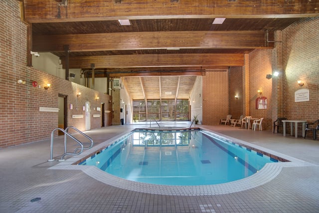 Indoor swimming pool with ample seating areas and large windows overlooking greenery.
