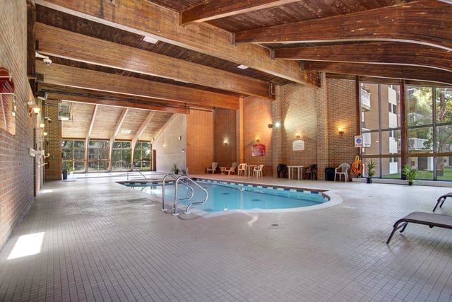 Indoor swimming pool with lounge chairs and seating area.