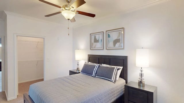 Bedroom with a queen-size bed, two nightstands, lamps, and a ceiling fan.