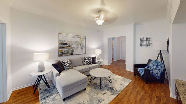 Living room in a modern apartment with a gray sectional, round coffee table, and lamps.