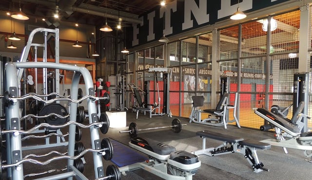Indoor gym with weight racks, benches, and machines in a modern fitness center.