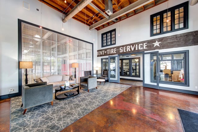 Lobby seating area with a glass divider, exposed wood ceiling, and a vintage sign.