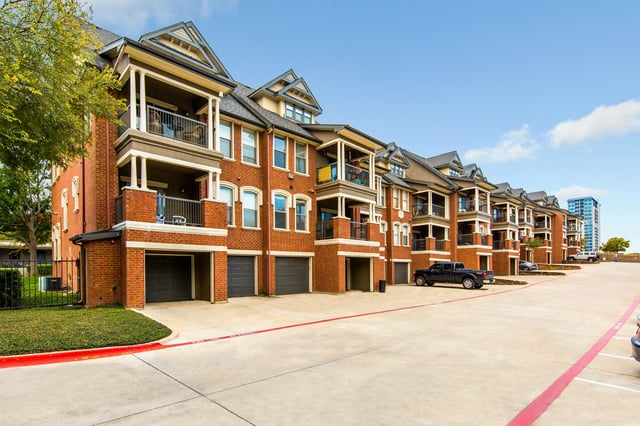 Exterior row of brick apartment buildings with garages and balconies.