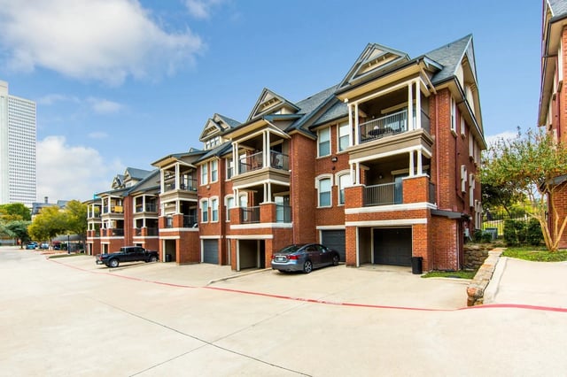 Exterior view of a brick apartment building with multiple balconies and attached garages.