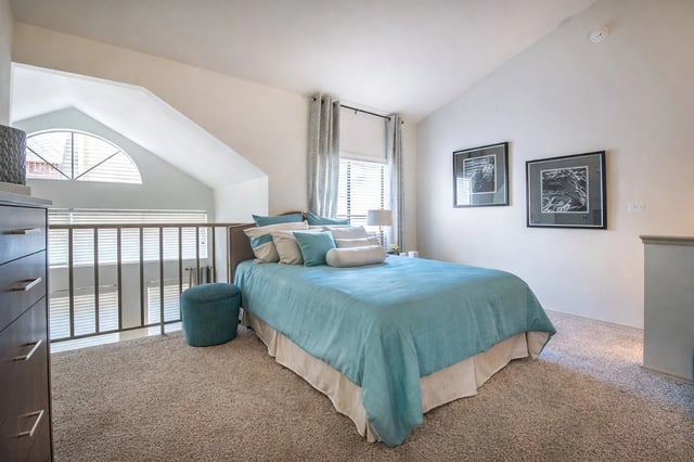 A bedroom with a bed with blue linens, a dresser, and framed artwork.