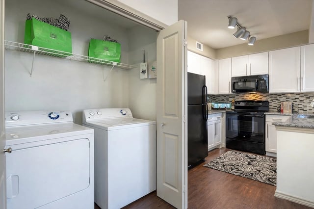 Washer, dryer, and kitchen area in an apartment.