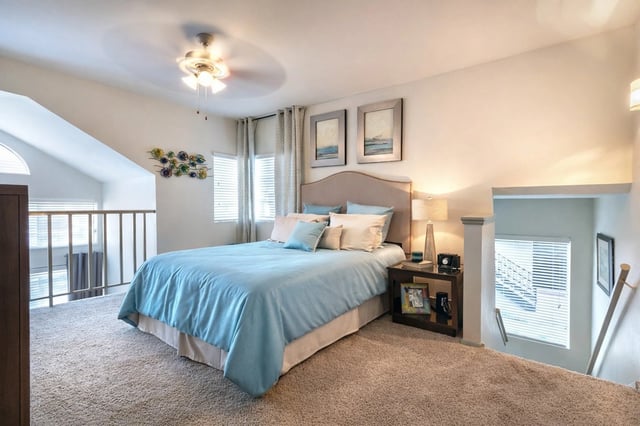 Loft bedroom with a king-size bed, blue bedding, and a ceiling fan.