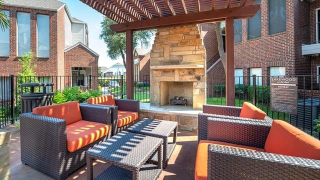 Outdoor seating area with a stone fireplace and lounge furniture.