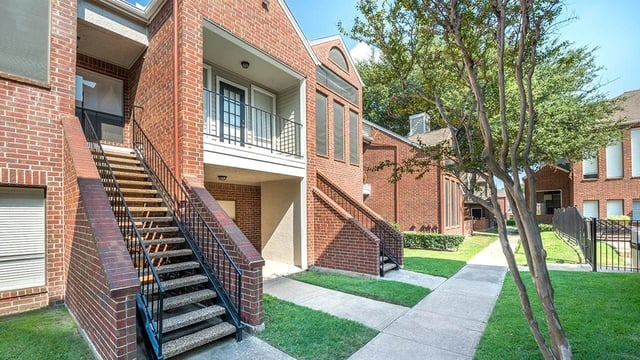 Exterior view of brick apartment buildings with outdoor staircases and walkways.