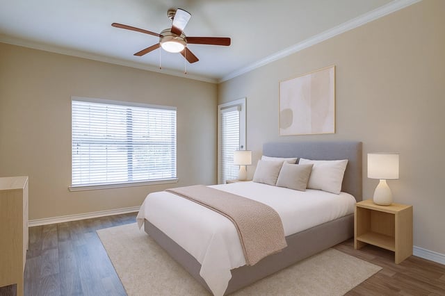 A staged bedroom with a king-size bed, nightstands, and a ceiling fan.