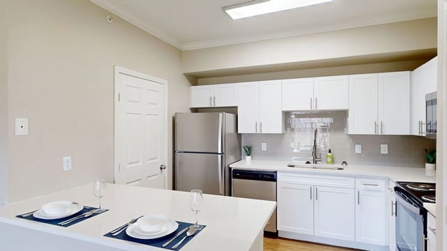 Modern kitchen with stainless steel appliances, white cabinets, and a breakfast bar.