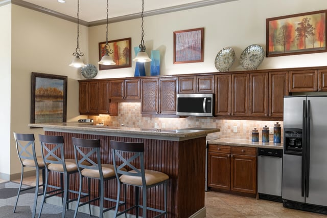 Kitchen with a breakfast bar and stools, stainless steel appliances, and wooden cabinetry.