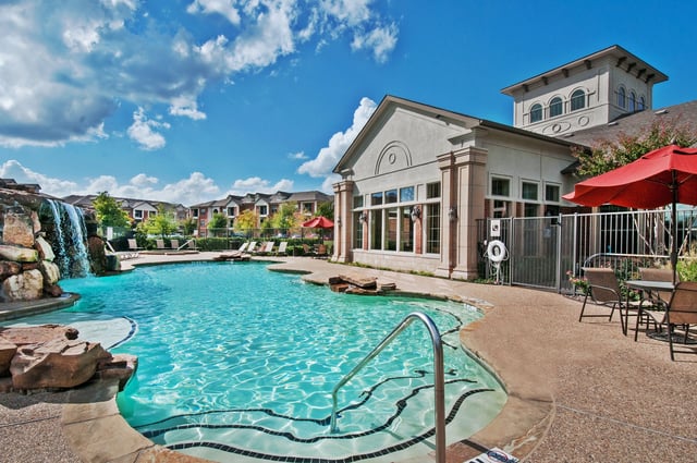 Resort-style swimming pool with waterfall and lounge chairs.