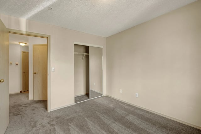 Empty bedroom with a closet and an open doorway leading to a hallway.