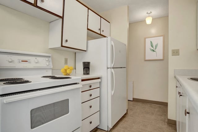 White electric stove and refrigerator in apartment kitchen.