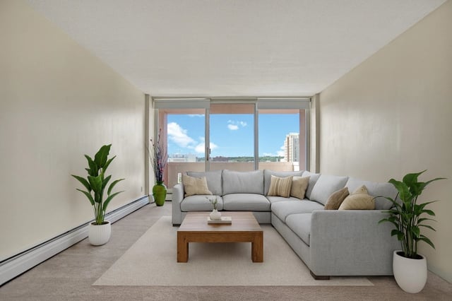Modern living room with a large sectional sofa, wooden coffee table, and large windows with a city view.