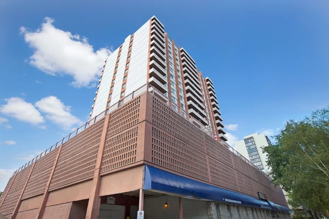 Exterior view of a tall apartment building with balconies against a blue sky.