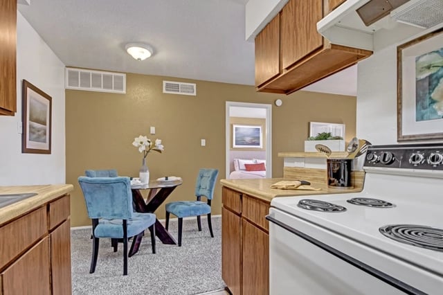 Kitchen and dining area with blue velvet chairs and a round glass-top table.