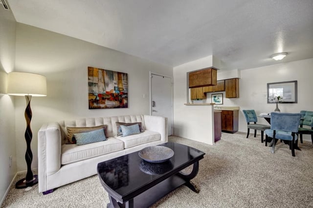 Living room with a white sofa, coffee table, and dining area with blue chairs.