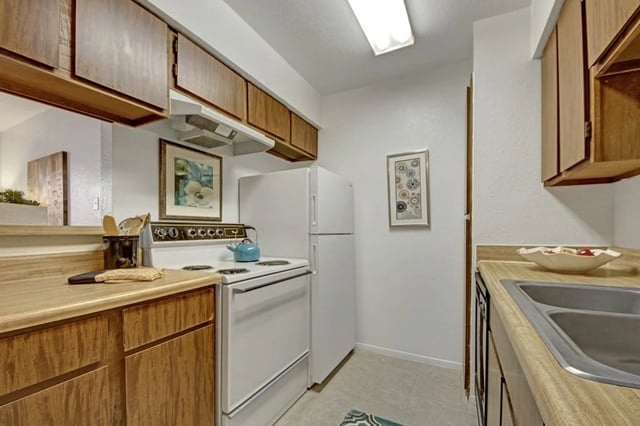 Kitchen with wood cabinets, white appliances, and a sink.