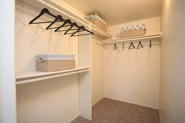 Empty walk-in closet with shelves and hangers.