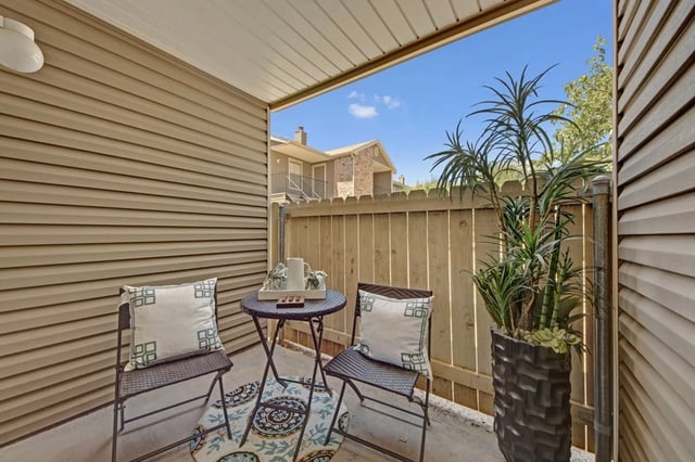 Balcony with two chairs, a table, and plants.