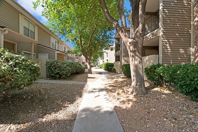 A pathway winds between apartment buildings and lush greenery.