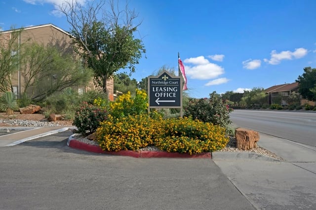 Northridge Court Leasing Office sign with arrow pointing left, surrounded by flowering bushes and landscaping.
