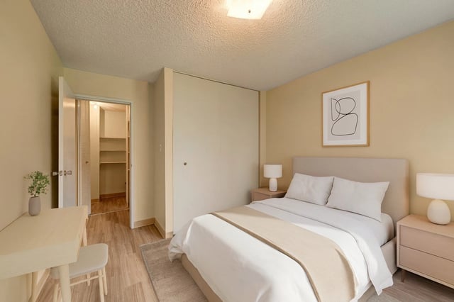 Bedroom with a queen-size bed, nightstands, desk, and closet.