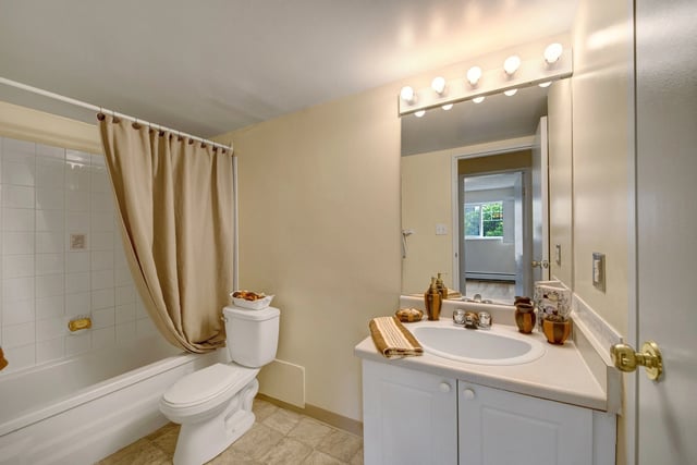 Clean and bright bathroom with a bathtub, toilet, and vanity with mirror.
