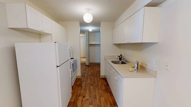 Kitchen with white cabinets, refrigerator, and sink.