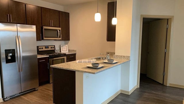 Modern kitchen with stainless steel appliances, granite countertops, and dark wood cabinets.
