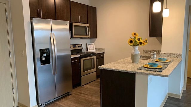 Modern kitchen with stainless steel appliances and granite countertops.