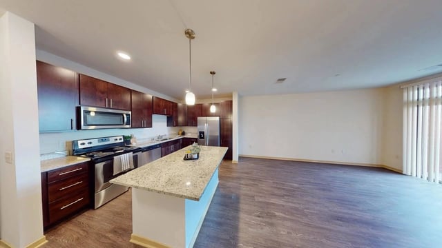 Modern kitchen with dark cherry cabinets, granite countertops, stainless steel appliances, and an island.