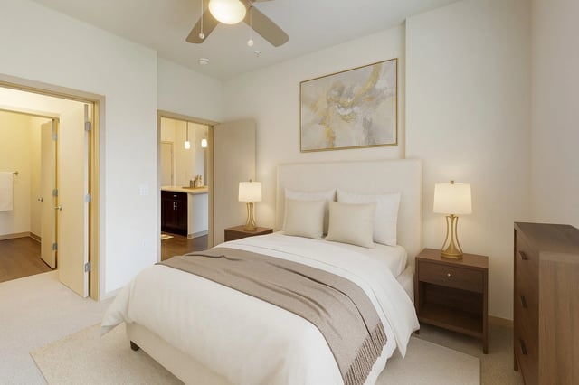 Bedroom with a queen-sized bed, nightstands, dresser, and a view into the kitchen and bathroom.