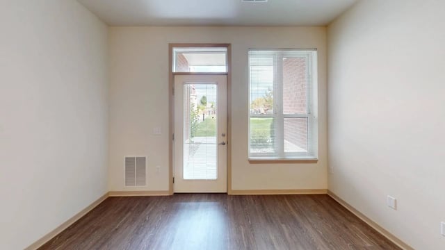 Empty living room with a door leading outside and a window.