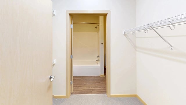 View of a bathroom with a bathtub and shower, and an adjacent closet with shelving.