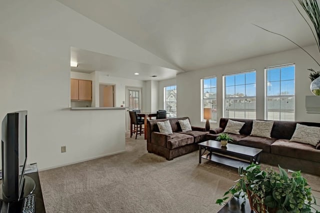 Spacious living room with a couch and coffee table, open to a kitchen area with a bar.