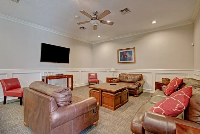 Clubhouse lounge with leather sofas, chairs, a coffee table, and a TV.