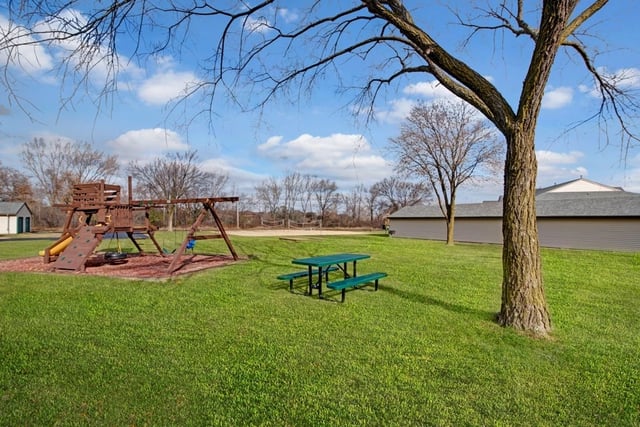 Playground and picnic area with volleyball court in the background.