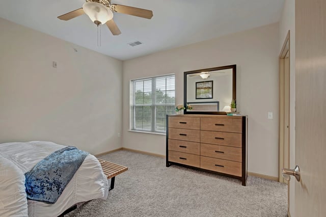 Bedroom with a dresser, mirror, and bed.