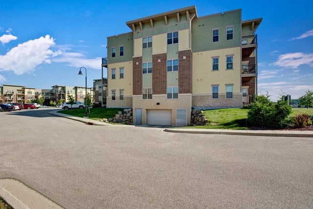 Exterior view of apartment buildings with a paved road and parking lot in the foreground.