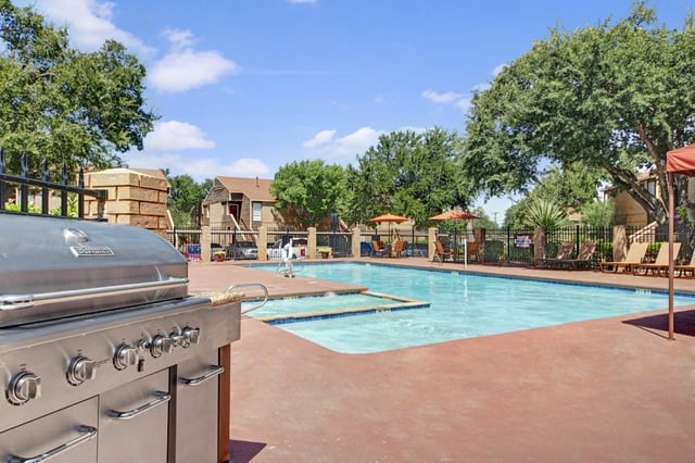Outdoor swimming pool with lounge chairs and a built-in grill.