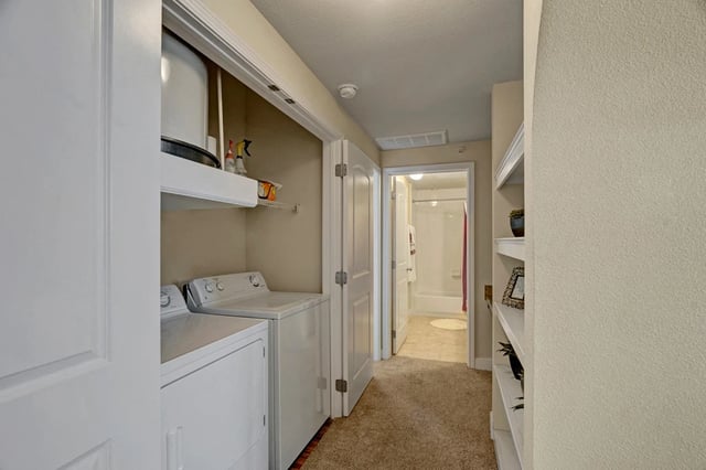 Hallway with washer, dryer, and access to bathroom.