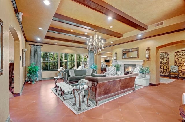 Elegant clubhouse lounge with fireplace and large windows overlooking trees.