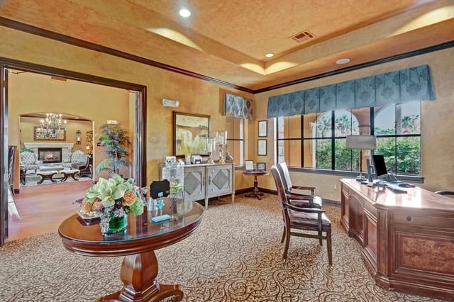 Reception desk and seating area with a view of a lounge with fireplace.