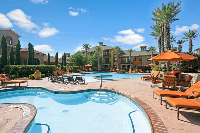 Resort-style swimming pool with lounge chairs and umbrellas.