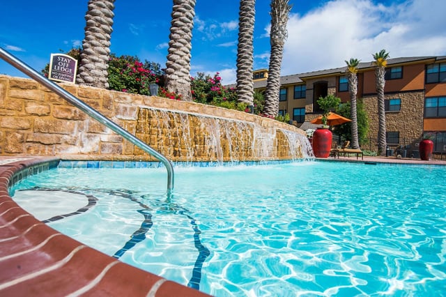 Resort-style swimming pool with a waterfall feature and palm trees.
