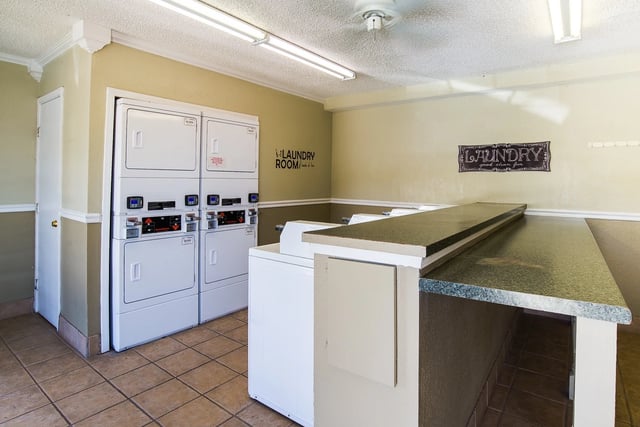 Communal laundry room with stacked washers and dryers and a long folding counter.