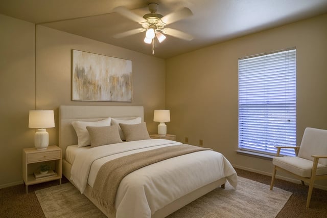 Bedroom with a neatly made bed, two nightstands, lamps, a ceiling fan, and a window with blinds.
